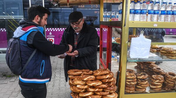 Мужчина покупает хлебобулочные изделия на одной из улиц в районе Кадыкей города Стамбул