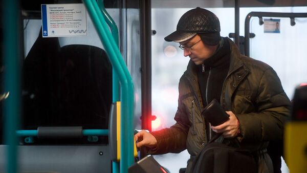 Пассажир прикладывает билет к валидатору в автобусе