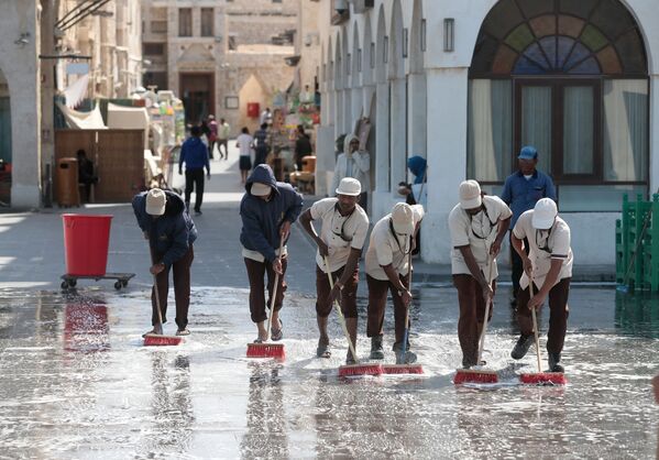 Мужчины моют одну из улиц в городе Доха
