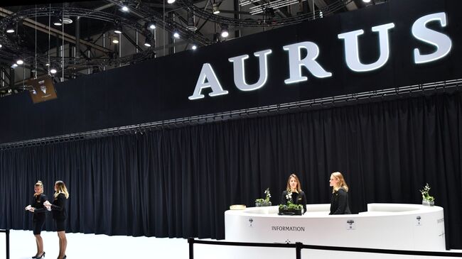 Девушки у информационной стойки стенда Aurus на Женевском автосалоне