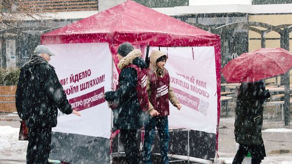 Прохожие и волонтеры у агитационной палатки с печатной продукцией кандидата и действующего президента Украины Петра Порошенко