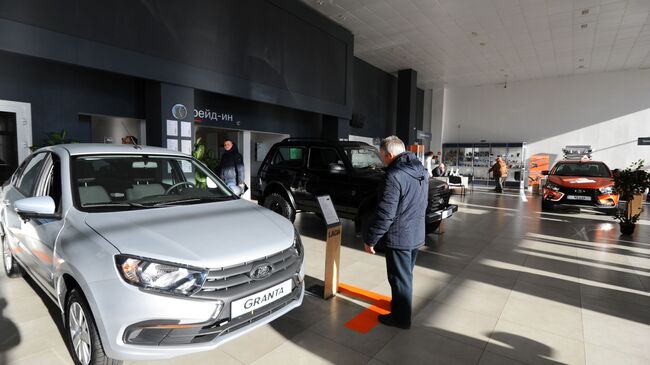 Посетитель рассматривает автомобиль Lada Granta в демонстрационном зале автоцентра