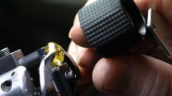 Сотрудник рассматривает бриллиант в цехе огранки ООО Бриллианты Алроса в Москве