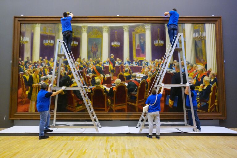 Сотрудники музея вешают картину Торжественное заседание Государственного совета 7 мая 1901 года в день столетнего юбилея со дня его учреждения во время подготовки выставки Ильи Репина в Третьяковской галерее на Крымском валу