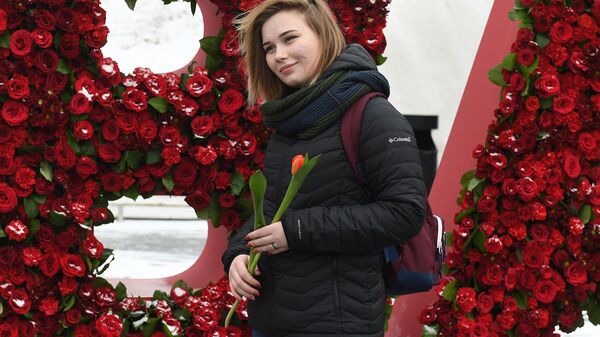 Девушка с тюльпаном, подаренным волонтерами движения Мосволонтер в рамках добровольческой акции Вам, любимые! , в парке Зарядье в Москве