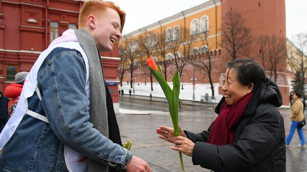 Волонтер движения Мосволонтер в рамках добровольческой акции Вам, любимые! дарит цветы и поздравляет женщину с Международным женским днем на Красной площади