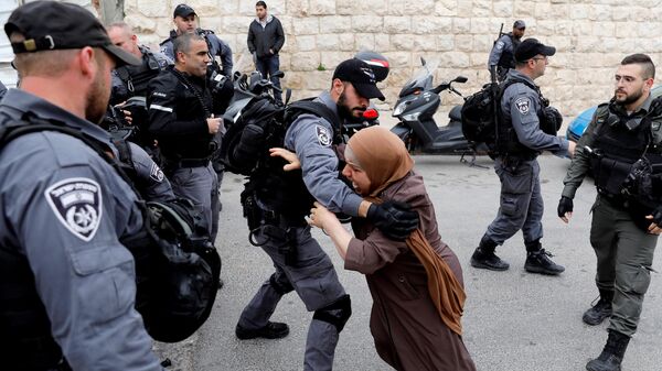 Израильский полицейский оттесняет палестинскую женщину 