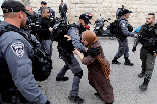 Израильский полицейский оттесняет палестинскую женщину возле Старого города Иерусалима
