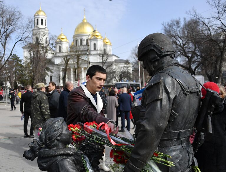 Мужчина оставляет цветы у памятника Вежливым людям во время мероприятий, посвященных 5-й годовщине Общекрымского референдума 2014 года и воссоединения Крыма с Россией, в сквере Республики в Симферополе