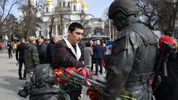 Мужчина оставляет цветы у памятника Вежливым людям во время мероприятий, посвященных 5-й годовщине Общекрымского референдума 2014 года и воссоединения Крыма с Россией, в сквере Республики в Симферополе