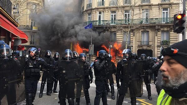 Полиция перед горящим зданием в Париже во время акции протеста желтых жилетов. 16 марта 2019