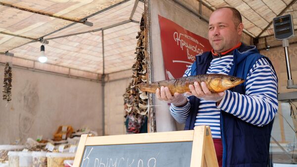 Продавец демонстрирует рыбу для продажи на ярмарке в рамках фестиваля Крымская весна в Краснодаре