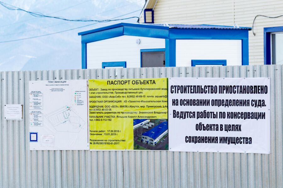 Информационные плакаты на заборе завода по производству питьевой бутилированной воды ООО Аквасиб в поселке Култук