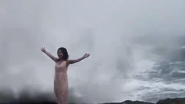 Кадр из видео, в котором девушку захлестнула огромная волна