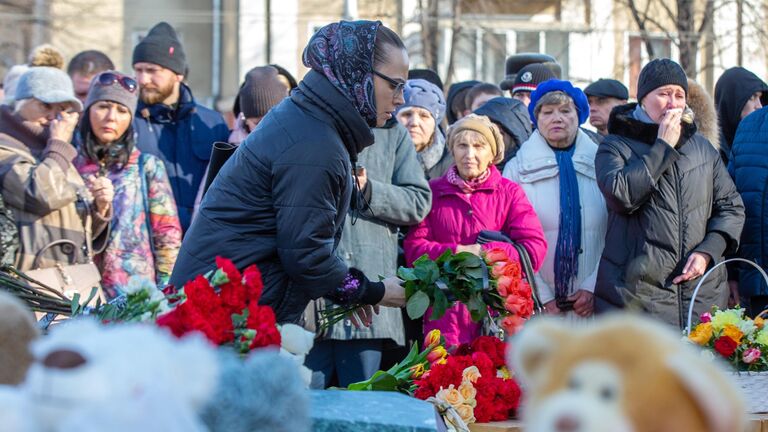 Девушка возлагает цветы к мемориалу в память о жертвах пожара в торгово-развлекательном центре Зимняя вишня в Кемерово
