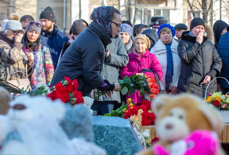 Девушка возлагает цветы к мемориалу в память о жертвах пожара в торгово-развлекательном центре Зимняя вишня в Кемерово