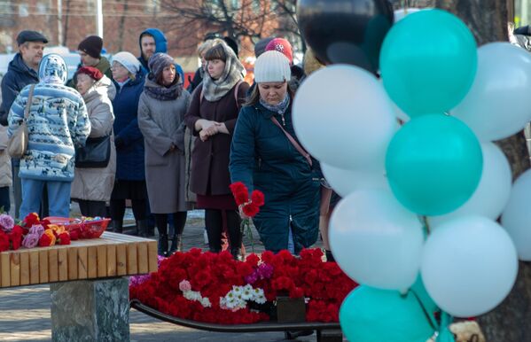 Девушка возлагает цветы к мемориалу в память о жертвах пожара в торгово-развлекательном центре Зимняя вишня в Кемерово