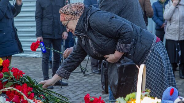 Женщина возлагает цветы к мемориалу в память о жертвах пожара в торгово-развлекательном центре Зимняя вишня в Кемерово