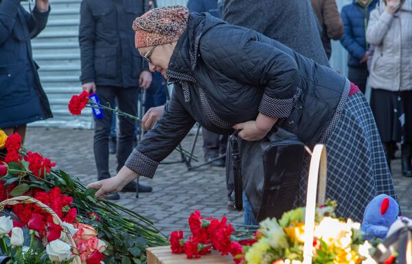 Женщина возлагает цветы к мемориалу в память о жертвах пожара в торгово-развлекательном центре Зимняя вишня в Кемерово