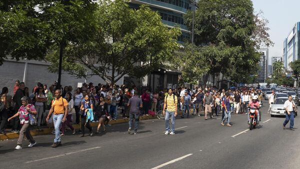 Люди идут по улице в Каракасе во время второго отключения электроэнергии в городе