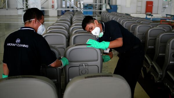 Работники клининговой компании моют сиденья в ангаре международного аэропорта Сукарно Хатта, Индонезия