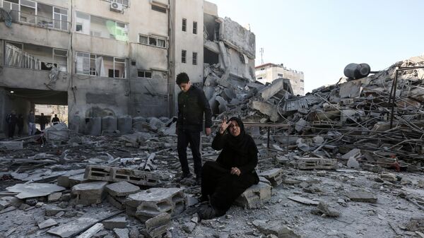 Палестинцы возле здания, разрушенного в результате ударов Израиля
