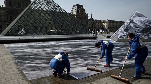 Волонтеры во время подготовки инсталляции французского современного художника и фотографа Жана Рене в главном дворе Лувра в Париже. 28 марта 2019 