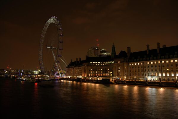 Колесо обозрения Лондонский глаз на набережной Темзы после отключения подсветки в рамках экологической акции Час Земли