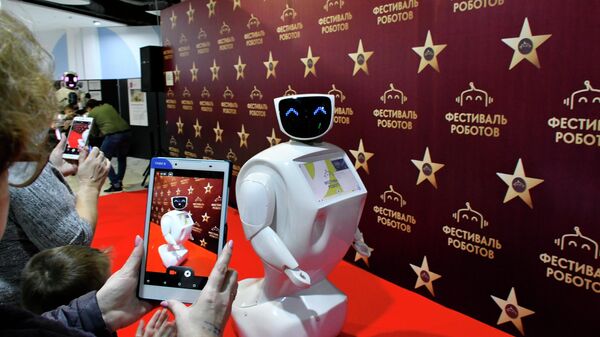 Посетители фотографируют интерактивного мобильного робота на колесной платформе Василия на фестивале роботов в Краснодаре