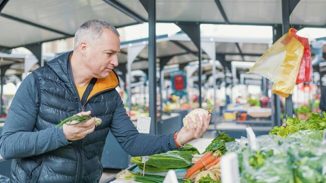 Мужчина выбирает овощи на рынке