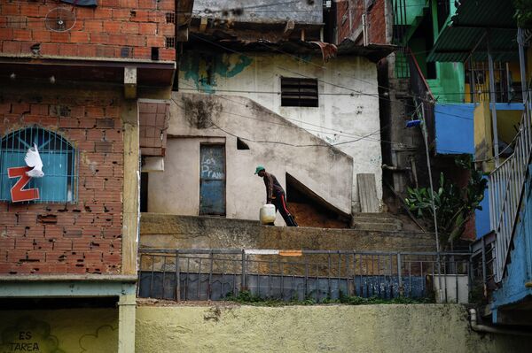 Мужчина несет воду к своему дому в районе Петаре в Каракасе