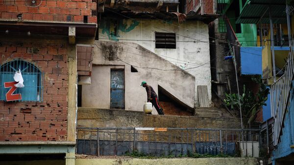 Мужчина несет воду к своему дому в районе Петаре в Каракасе