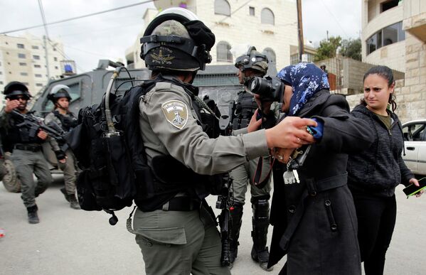 Израильский пограничник не дает фотографу сделать снимок палестинского дома в Бейт-Джале