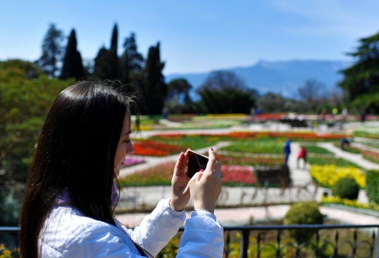 Девушка фотографирует в Никитском ботаническом саду в Крыму