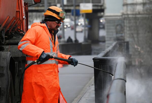 Сотрудник коммунальной службы моет ограду моста в Москве