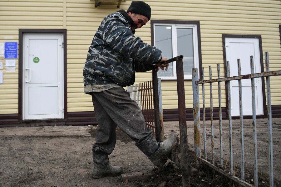 Мужчина очищает обувь от грязи в деревне Аполлоновка