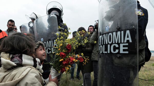 Дети дарят цветы сотрудникам полиции после беспорядков в лагере мигрантов в Диавате, Греция