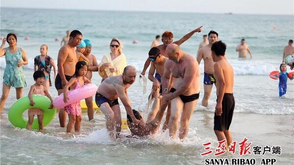 Россиянин Юрий Пасканный помогает спасти утопающего на пляже города Санья в Китае