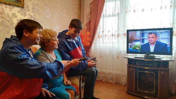 Никита Мамонов и Данил Алешин помогают пенсионерке Галине Никулиной разобраться с пультом