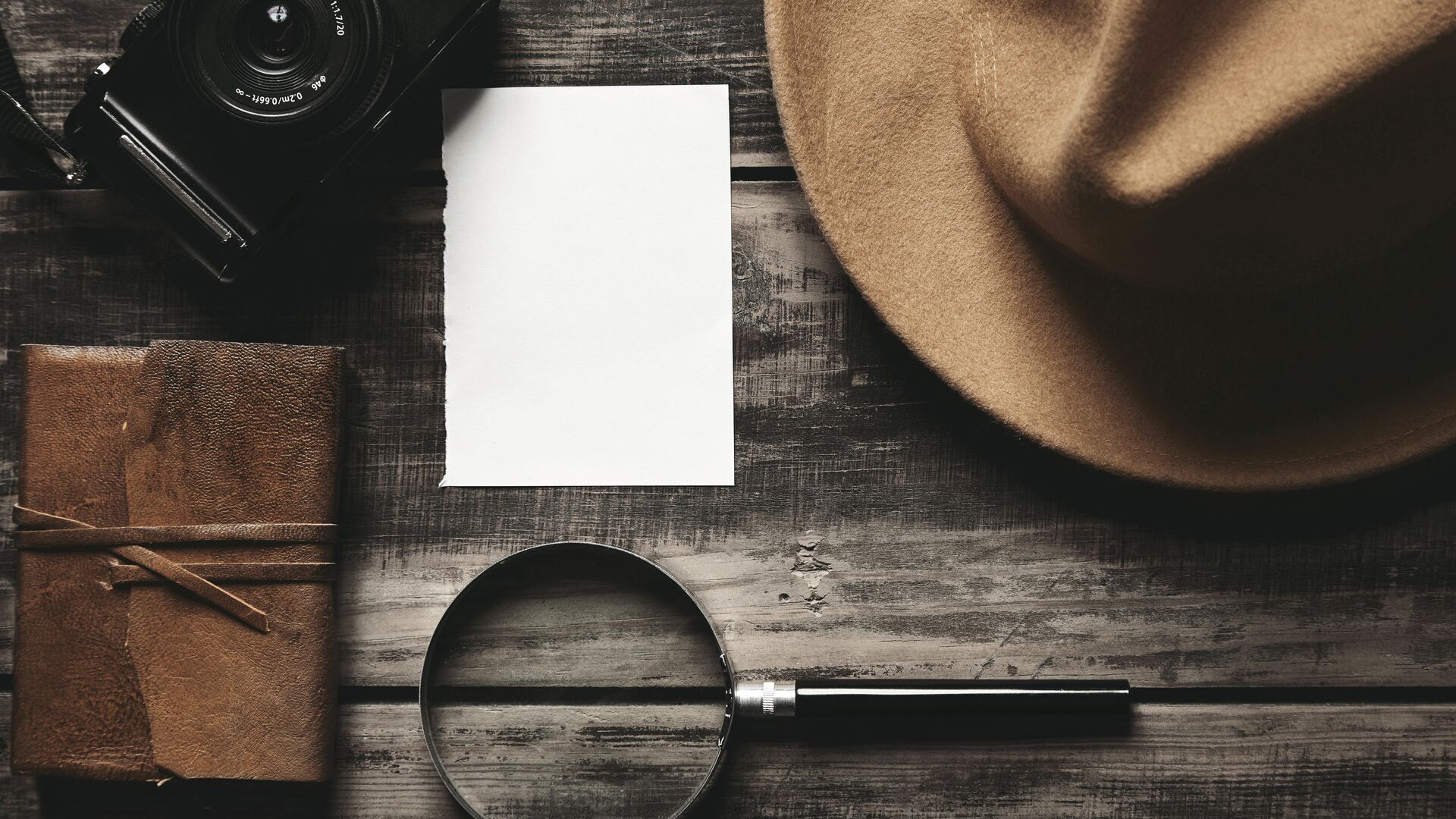  Закрытый блокнот в кожаном переплете, лист белой бумаги, фетровая шляпа, портативная  фотокамера и большая лупа на деревянном столе - РИА Новости, 1920, 04.02.2021
