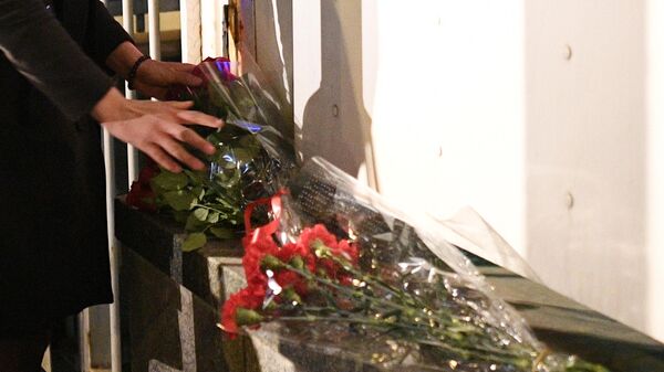 Девушка возлагает цветы у посольства Франции в связи с пожаром в соборе Парижской Богоматери  