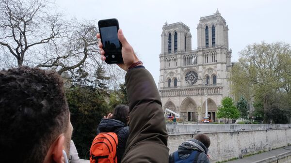 Прохожий фотографирует собор Парижской Богоматери после пожара