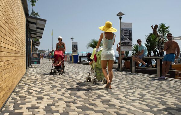 Мамы с колясками гуляют на набережной вдоль Массандровского пляжа в Ялте