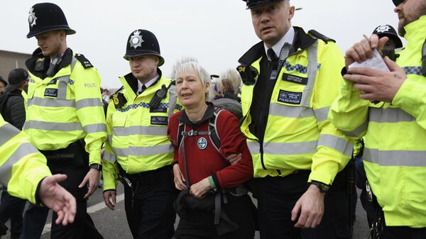 Сотрудники полиции задерживают участницу акции протеста, организованной  Extinction Rebellion, против загрязнения окружающей среды, проходящей в Лондоне. 16 апреля 2019