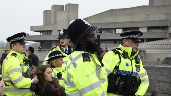 Сотрудники полиции задерживают участницу акции протеста против загрязнения окружающей среды, проходящей в Лондоне