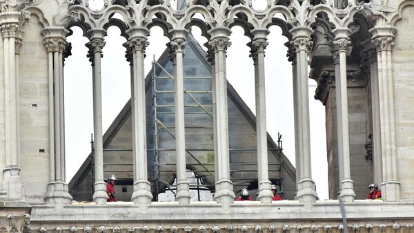 Пожарные осматривают крышу собора Парижской Богоматери после пожара