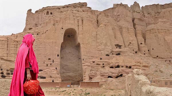 Женщина проходит мимо скал в Бамианской долине, где были высечены статуи. 2010 год