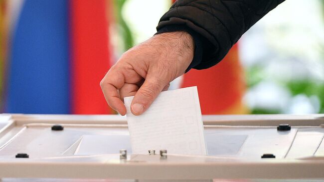 Избиратель опускает бюллетень в урну для голосования