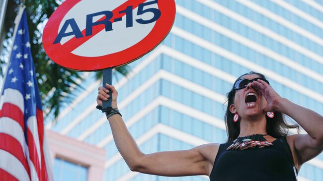 Девушка с плакатом против использования винтовки AR-15 во время акции протеста против ношения оружия в США 