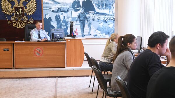 Люди сдают теоретические экзамены по правилам дорожного движения в отделении ГИБДД в Москве